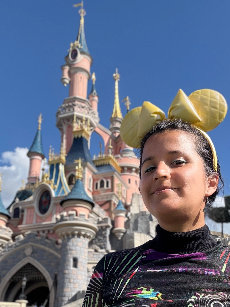 Paloma frente al castillo de la Bella Durmiente en Disneyland París con orejas Mickey doradas